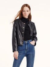 A woman wears a black leather jacket and gold earrings.